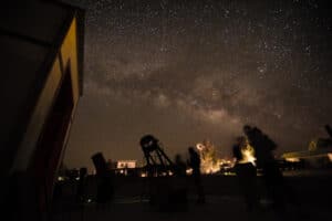A picture of the night skies with the milky way and a telescope