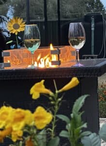 Yellow flowers in front of a fire pit with wine glasses