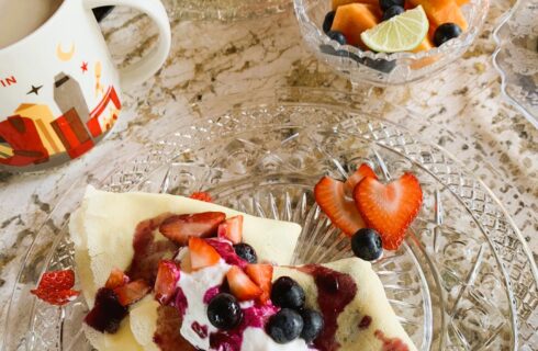 Ricotta filled crepes with whipped cream and berries, coffee, fresh fruit, scrambled eggs