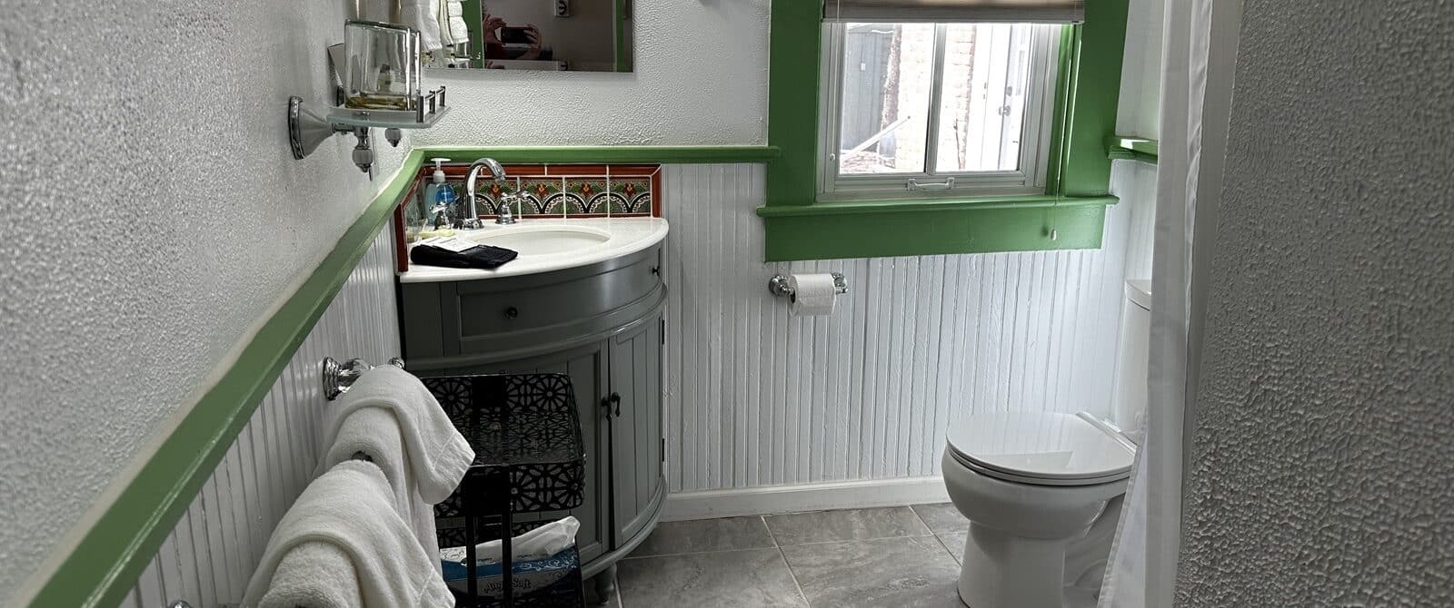 Bathroom with corner vanity, towel racks, window with natural light, toilet