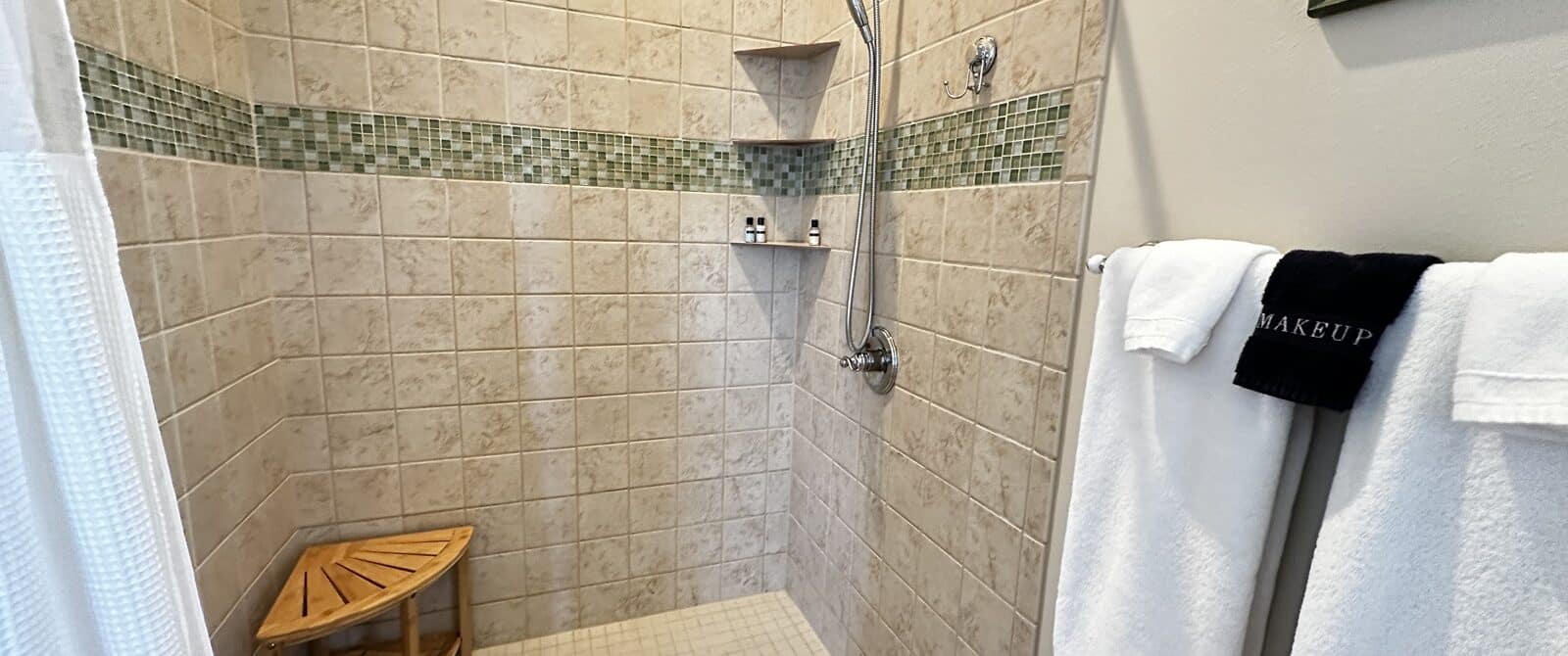 Walk-in shower with towels, shelves, bench, shampoo and conditioner
