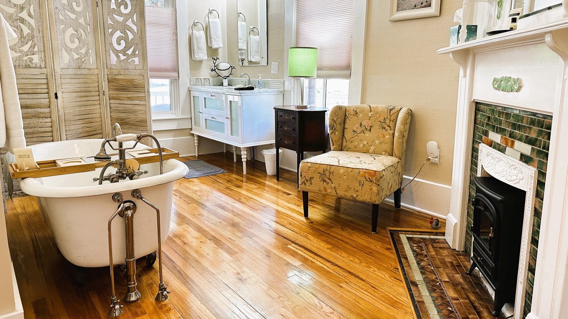 Elegant bathroom with large vanity, clawfoot tub, fireplace, windows and natural light