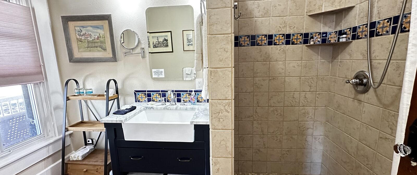 bathroom with large vanity, walk-in shower, mirror, art, shelving, towels