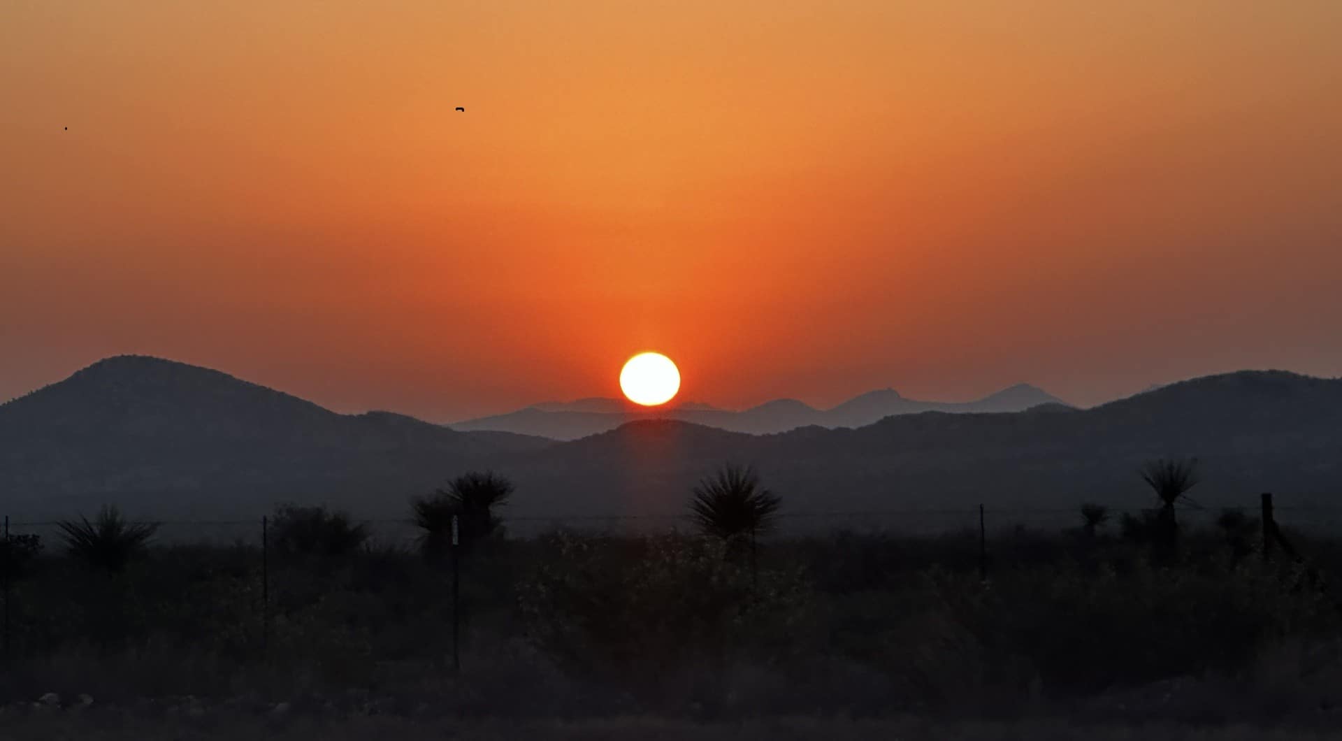 a sunrise over mountains with brilliant oranges and mountain shadows