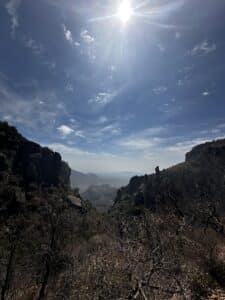 Blue skies, clouds, the sun, and distant mountains