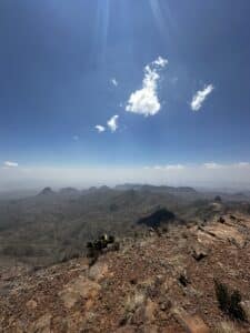 Layers if mountains in the distance, below blue skies and a whisp of clouds