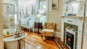 Elegant bathroom with large vanity, clawfoot tub, fireplace, windows and natural light