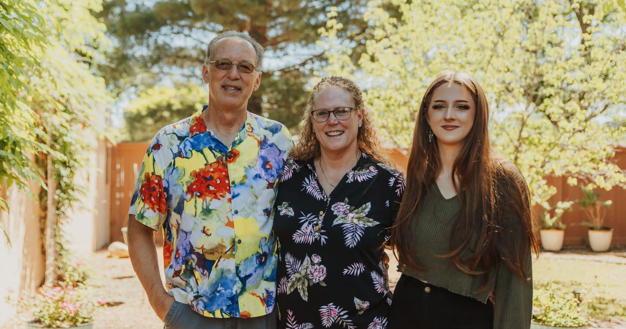 Three people standing outside in a garden