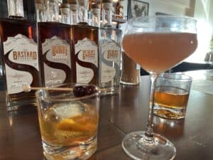 bottles of alcohol by Desert Ghost Distilling Company. Three bourbons and one vodka. there are also three mixed drinks in front of the bottles