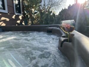 a bubbling hot tub with glasses of wine on the side and large cactus in the background