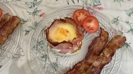 A breakfast dish containing what looks like eggs benedict as well as tomato slices and bacon