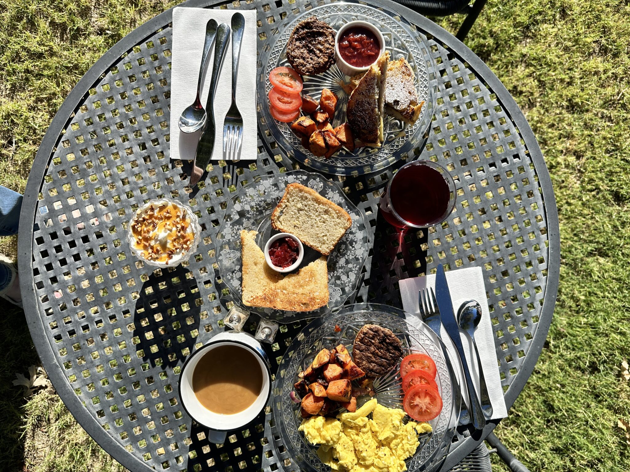 An outdoor table set with a variety of foods and drink