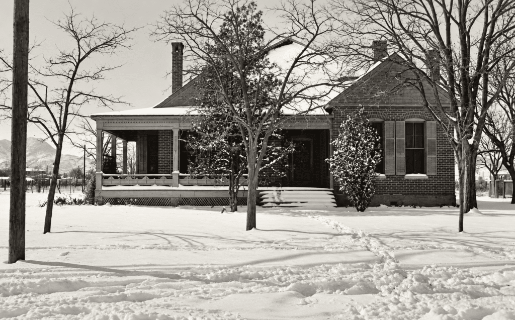 Historic black-and-white photograph of the Kincaid-Wade House in Alpine, Texas, after a snowfall, c. 1910s, with mountains visible in the distance.