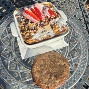 A croissant-based bread pudding topped with cream and sliced strawberries
