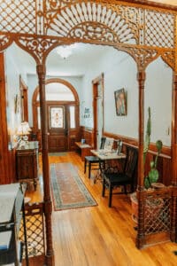 Original decorative spindlework framing the hallway of the Kincaid-Wade House, with hardwood floors, beadboard and the front entrance visible beyond.