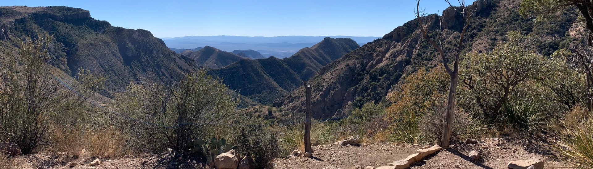 An expansive mountain range and valley covered in trees with blue skies above