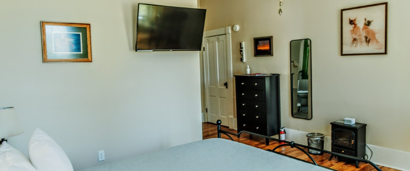 Bedroom with hardwood floors, black dresser and TV on the wall