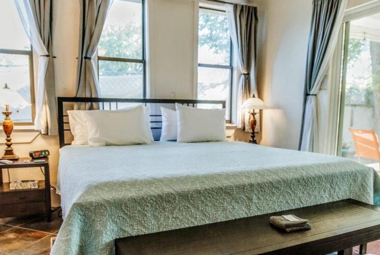 A bright airy bedroom with a king bed, large windows and a sliding door leading to an outdoor patio
