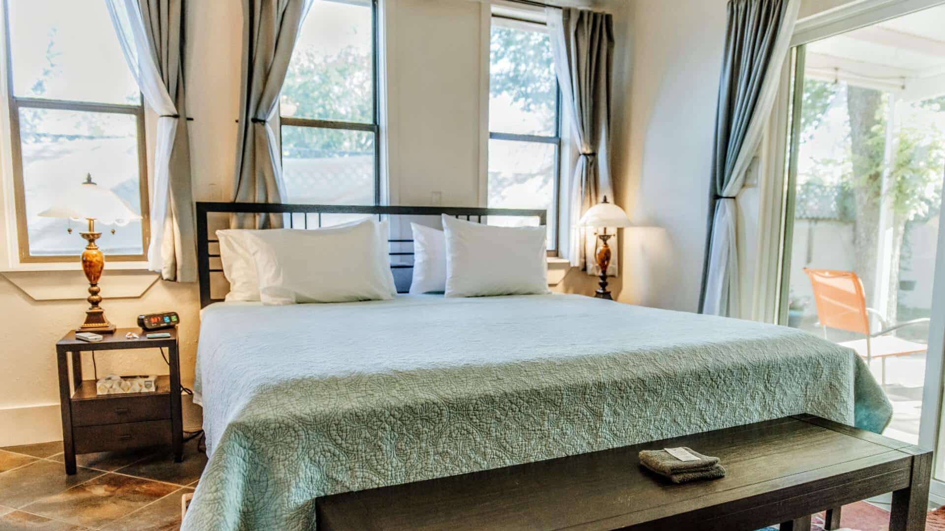A bright airy bedroom with a king bed, large windows and a sliding door leading to an outdoor patio