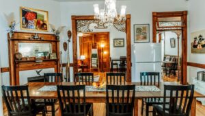Dining room of a home with rich wood detail, antique furnishings and two doorways into adjoining rooms